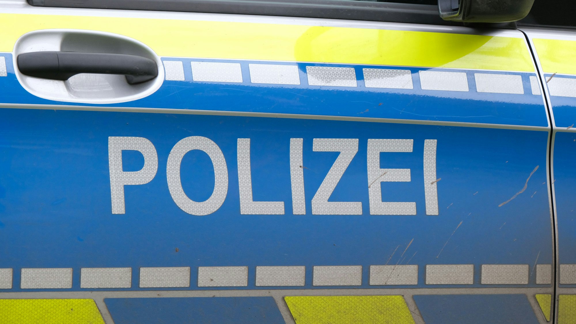 Die Aufschrift „Polizei“ auf der Türe eines Polizeiwagens.