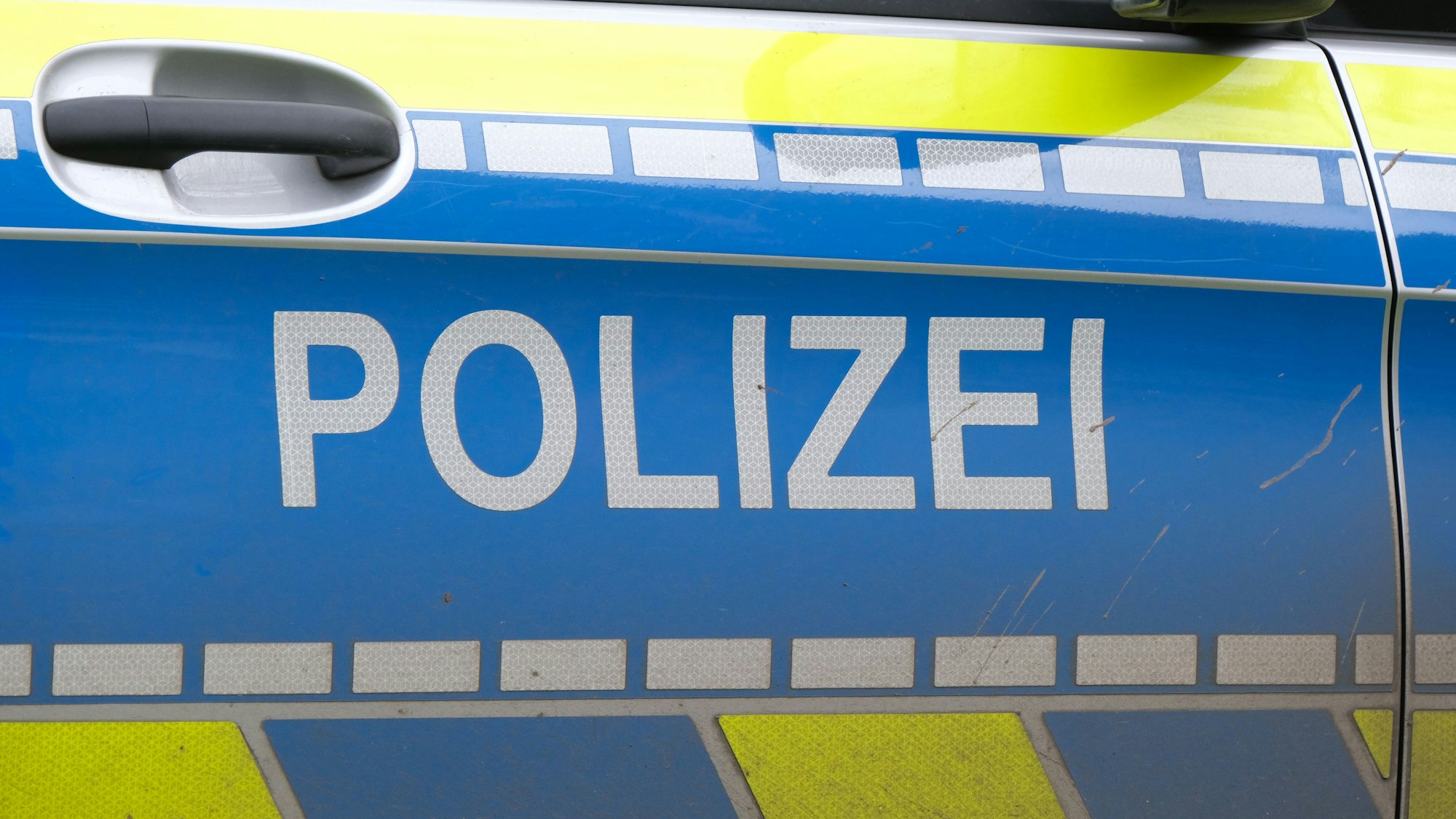 Autotür eines Polizei-Fahrzeugs mit weißer Aufschrift „Polizei“ auf blau.