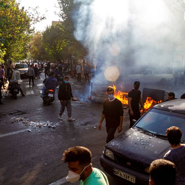 Menschen protestieren in Teheran auf der Straße und haben Barrikaden errichtet. Es brennen Feuer. Viele Demonstranten tragen Gesichtsmasken.