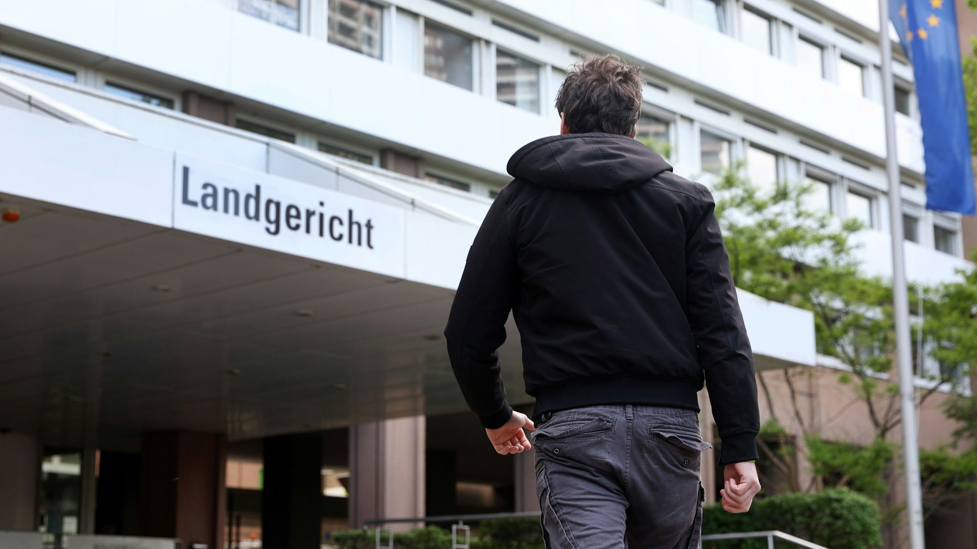 Ein Mann geht auf den Eingang zum Landgericht Köln zu.