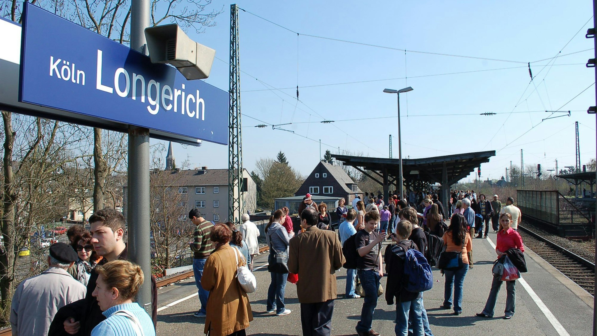Menschen warten auf dem Bahnsteig der Haltestelle Köln-Longerich.