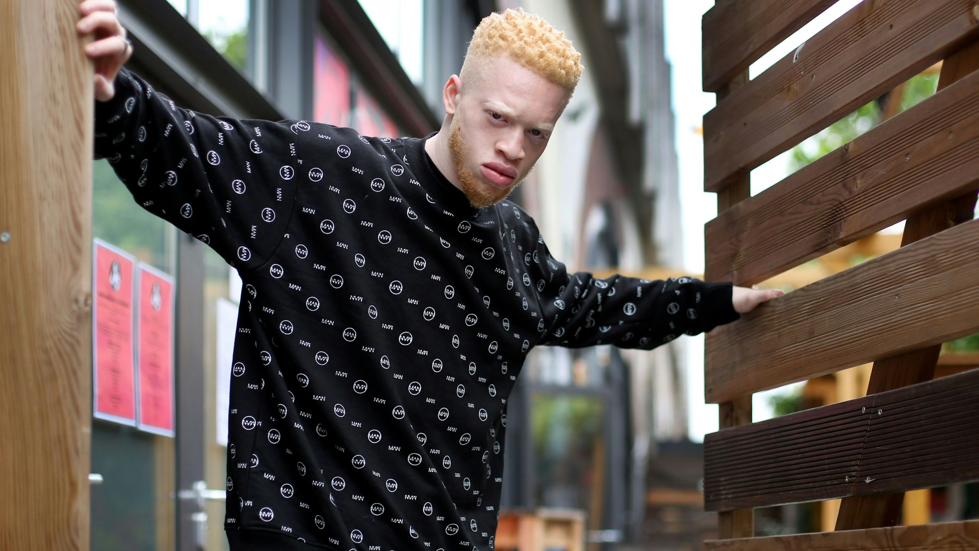 Der Rapper Albi X posiert für ein Foto zwischen zwei Zäunen und schau böse in die Kamera.