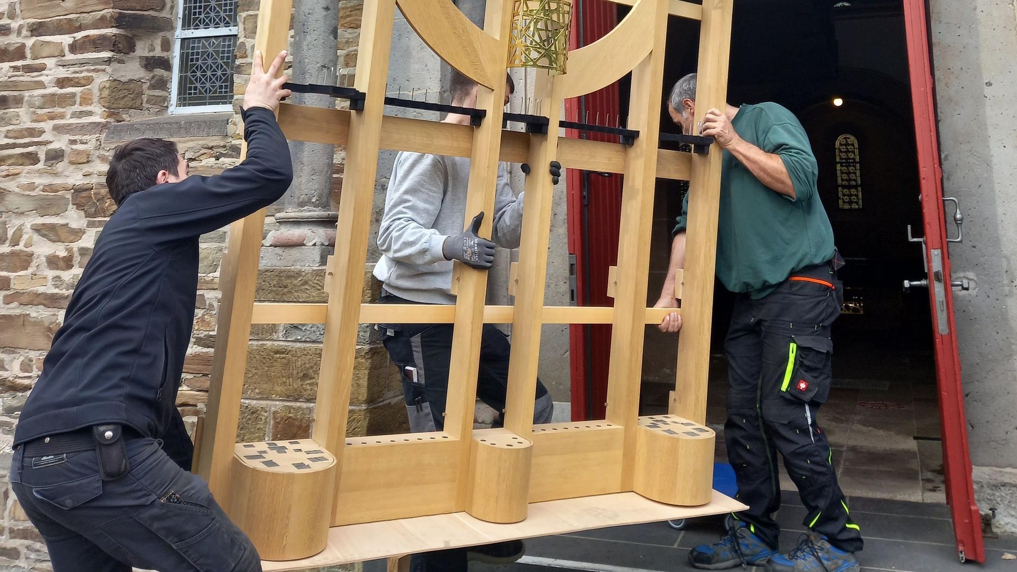 Arbeiter tragen ein Gerüstteil in die Basilika in Morsbach.