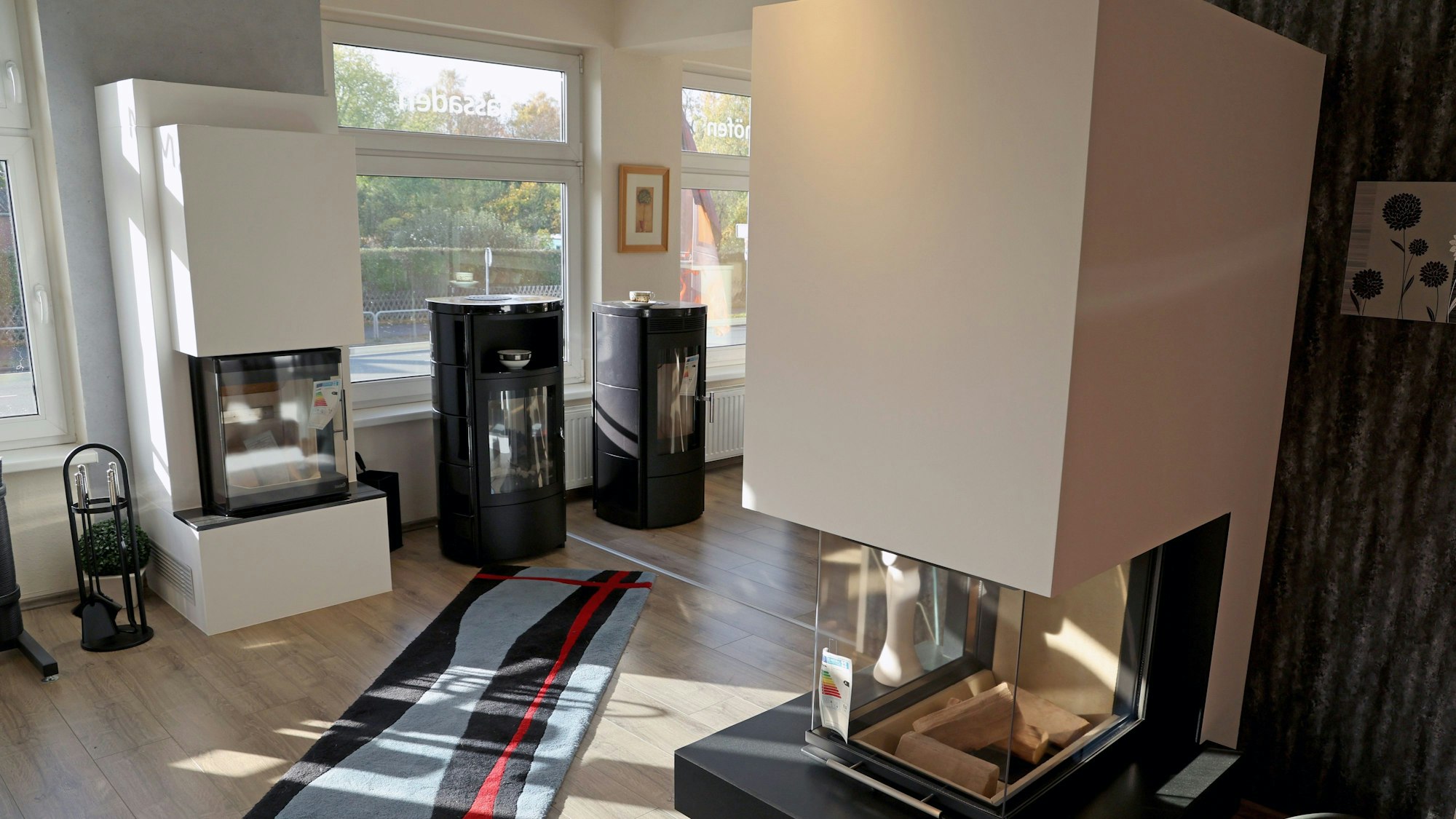 Es sind verschiedene Modelle von Kaminöfen zu sehen, die in einem Verkaufsraum stehen.