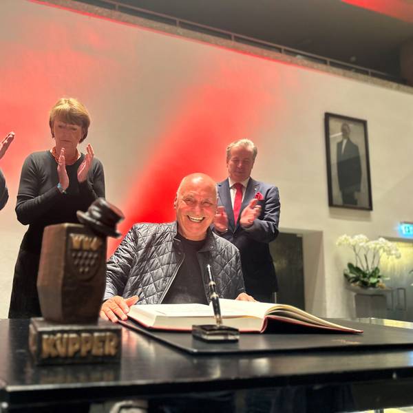 Rolly Brings wird mit dem Karl-Küpper-Preis ausgezeichnet und trägt sich ins Goldene Buch der Stadt Köln ein. Im Hintergrund applaudieren OB Henriette Reker, Festkomitee-Präsident Christoph Kuckelkorn und Bernhard Conin.