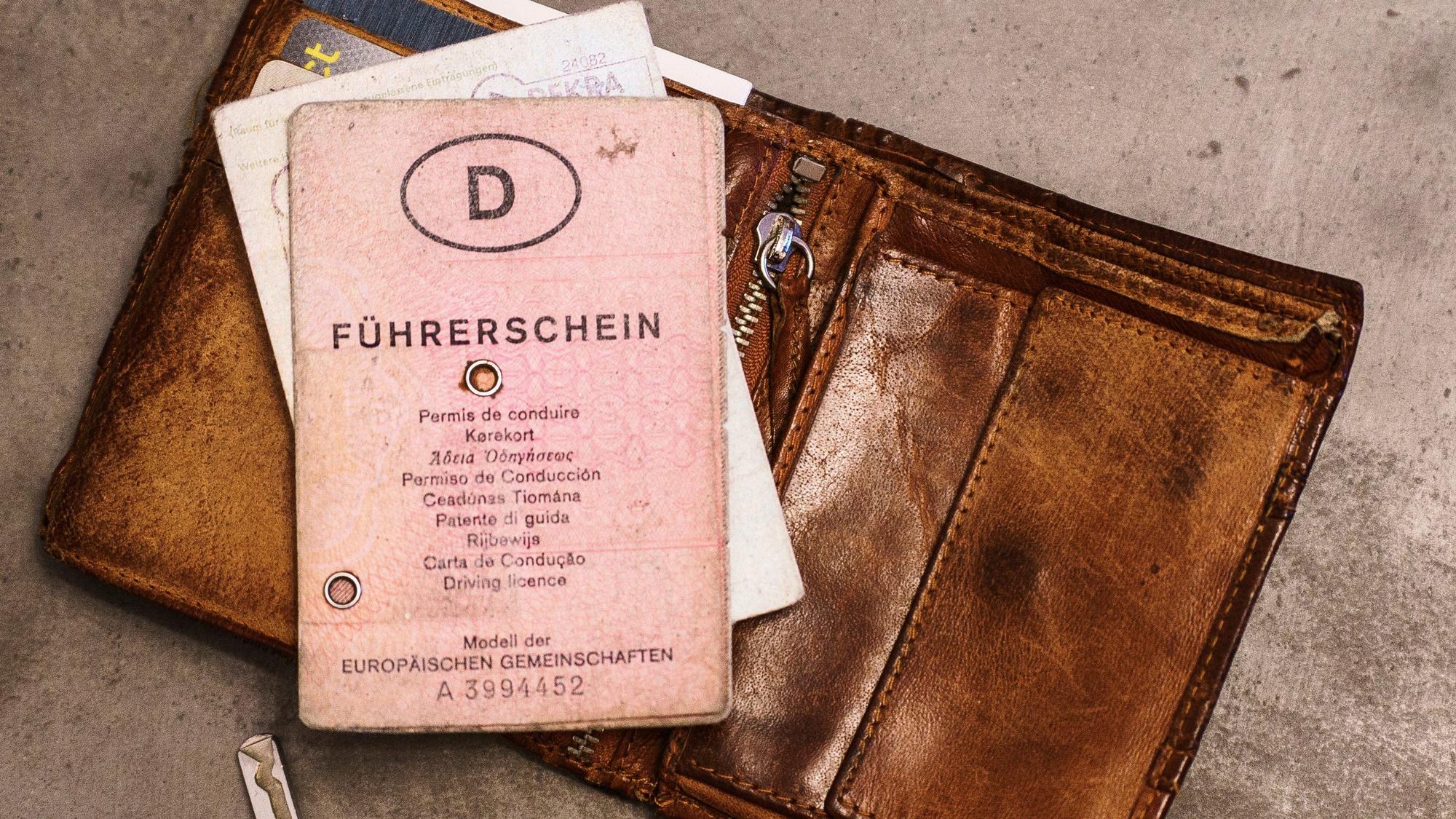 Ein «rosa Führerschein», ein Autoschlüssel, eine Geldbörse und ein Fahrzeugschein liegen auf dem Tisch.