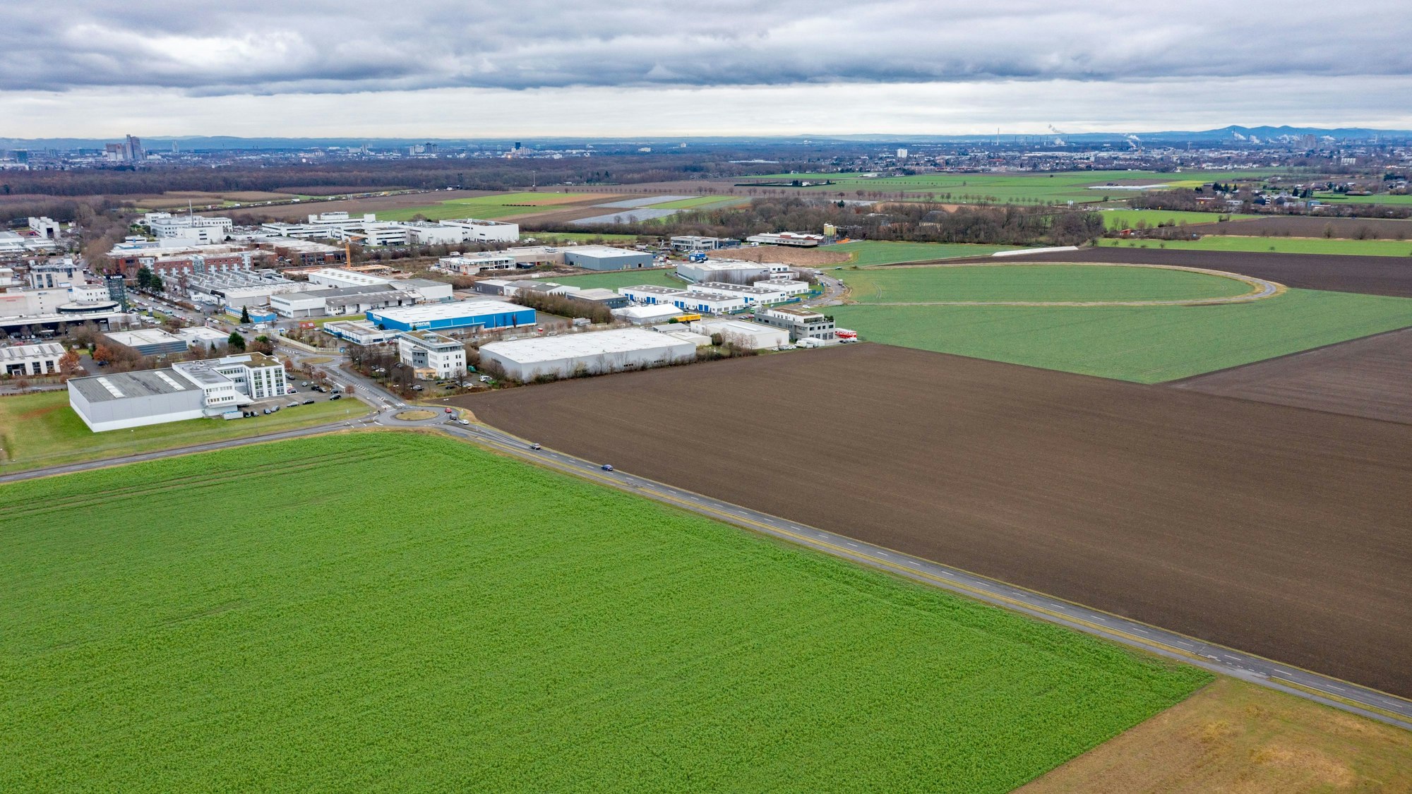 Das Bild zeigt einen unbebauten Acker in Marsdorf sowie einige Häuser.
