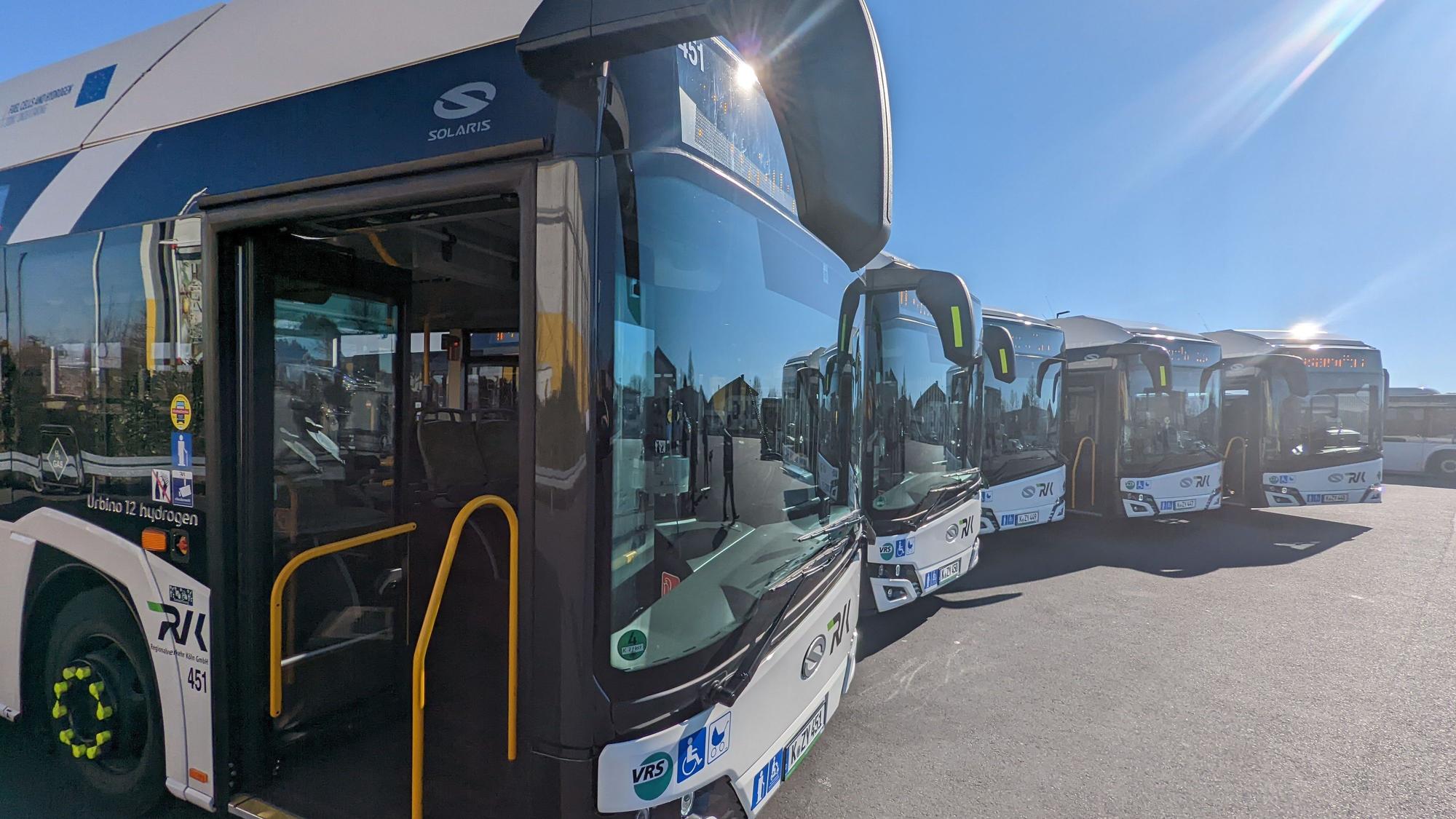 Fünf Busse stehen leicht versetzt nebeneinander auf dem Betriebshof.