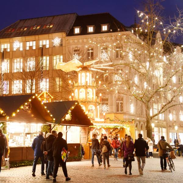 Der Weihnachtsmarkt auf dem Münsterplatz in 2021. Menschen laufen an Buden über einen hell erleuchteten Weihnachtsmarkt. (Symbolbild)