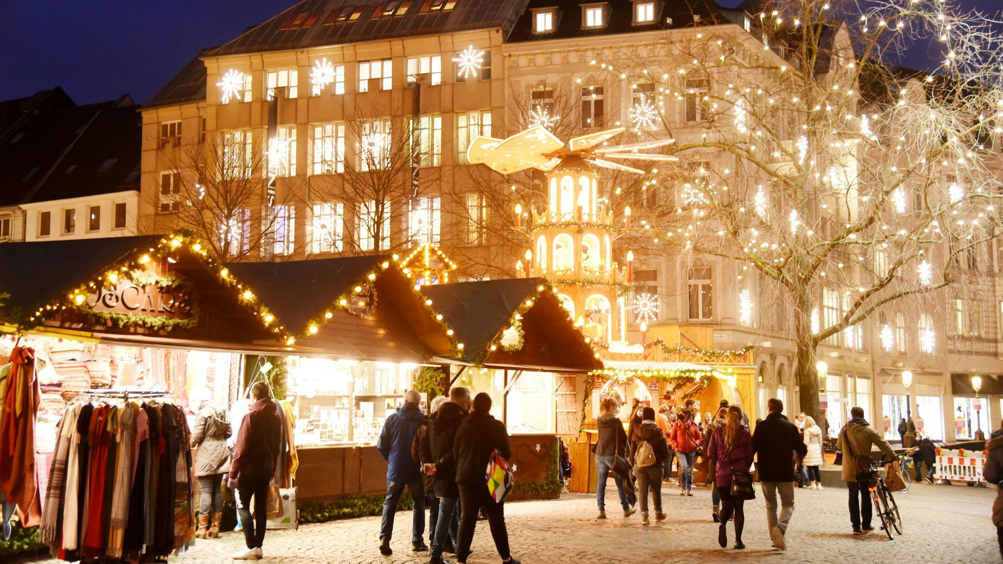 Der Weihnachtsmarkt auf dem Münsterplatz in 2021. Menschen laufen an Buden über einen hell erleuchteten Weihnachtsmarkt. (Symbolbild)