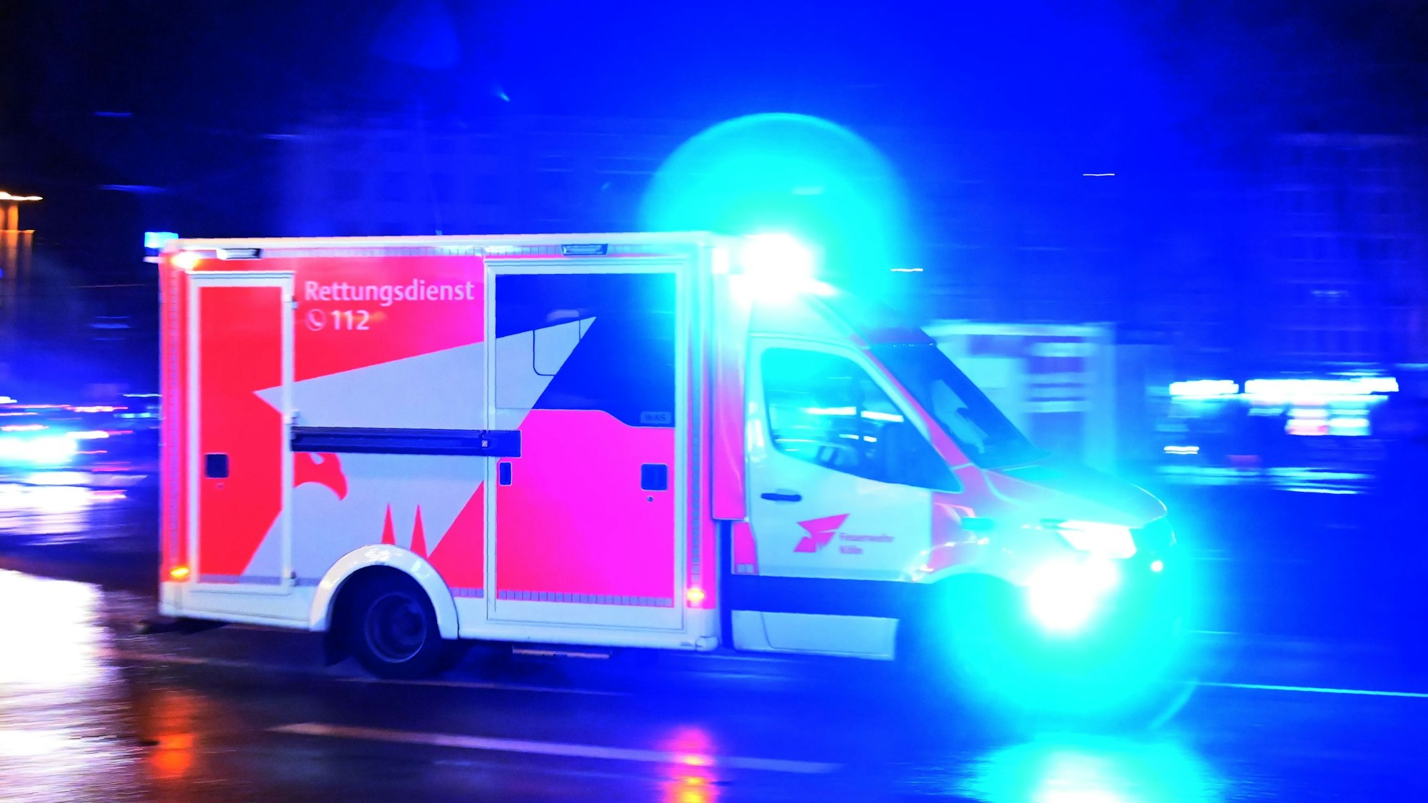 Zu sehen ist ein Rettungswagen der Feuerwehr Köln, der über den Neumarkt rast.