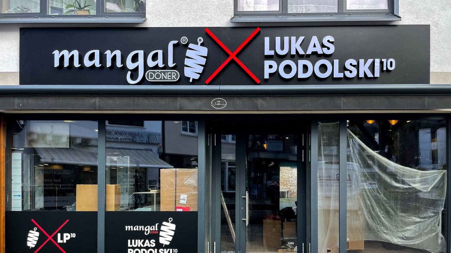 Über einem Ladenlokal ist ein Schild mit „mangal, Lukas Podolski“ angebracht, in den Innenräumen laufen noch Bauarbeiten.