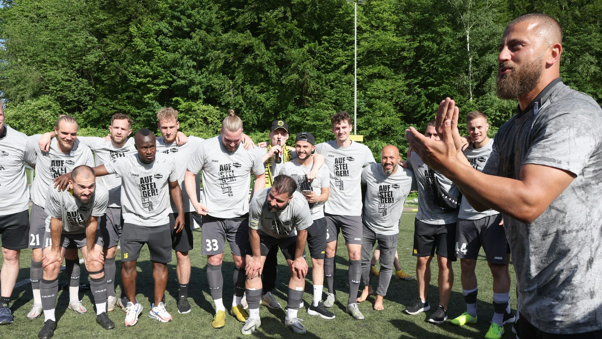 Die Mannschaft steht eng beienander, die Arme um die Schultern gelegt. Trainer Abdullah Keseroglu klatscht im Vordergrund in die Hände.