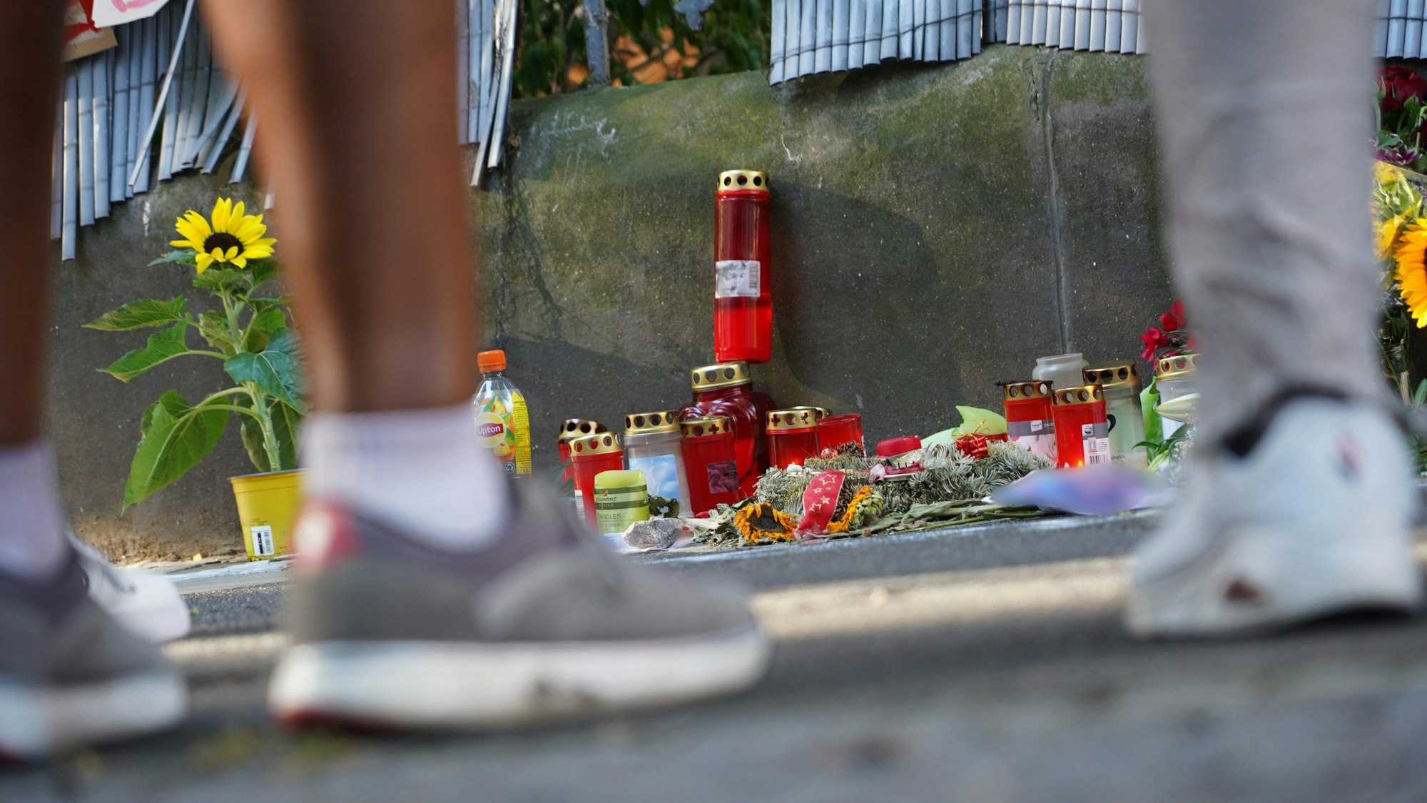 Menschen stehen vor einem Zaun, an dem mit Kerzen und Blumen eines von der Polizei erschossenen Jugendlichen gedacht wird. Nach den tödlichen Schüssen aus einer Maschinenpistole auf einen 16-Jährigen in Dortmund wird gegen vier weitere Polizisten ermittelt. Dabei geht es um den Einsatz von Pfefferspray und Tasern.