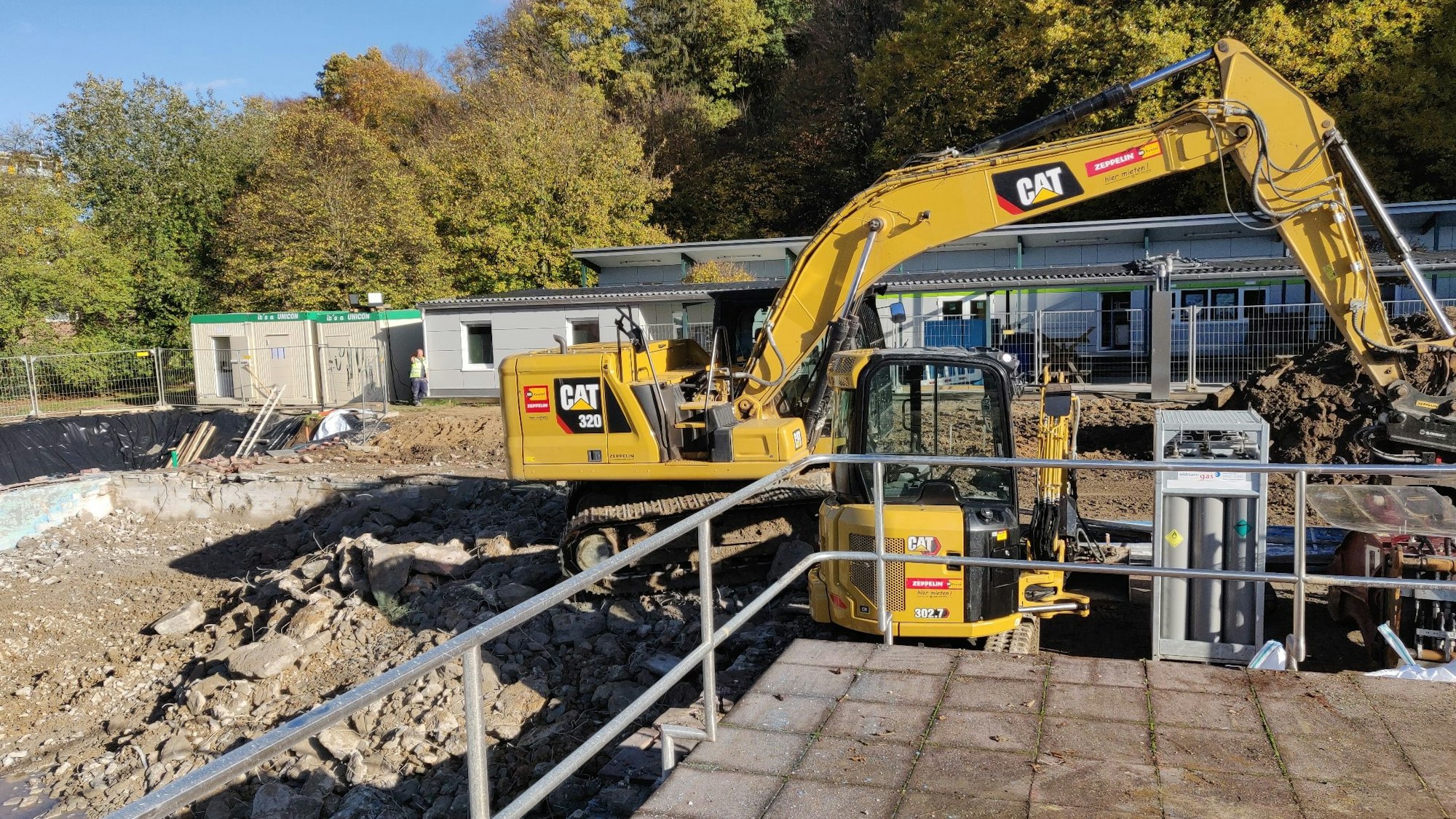 Auf dem Freibad-Gelände in Leichlingen stehen Bagger zwischen dem abgebrochenen Schwimmmeister-Haus und dem Umkleidetrakt.