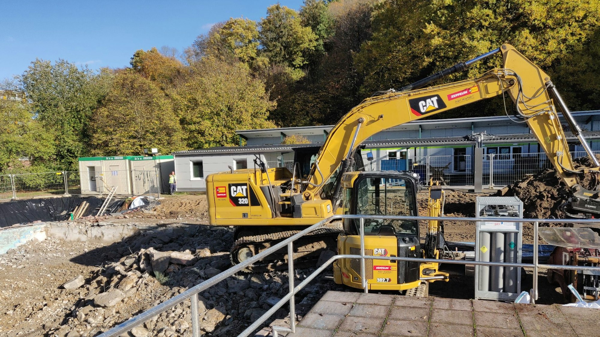 Blick vom abgebrochenen Schwimmeister-Haus Richtung Umkleidetrakt und Kiosk, die stehenbleiben.