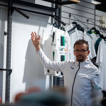 Wolfgang Fröhling, Sportgeschäft-Inhaber aus Zülpich, steht vor den Trikots von Borussia Mönchengladbach und Borussia Dortmund, ein Ständer ist leer.