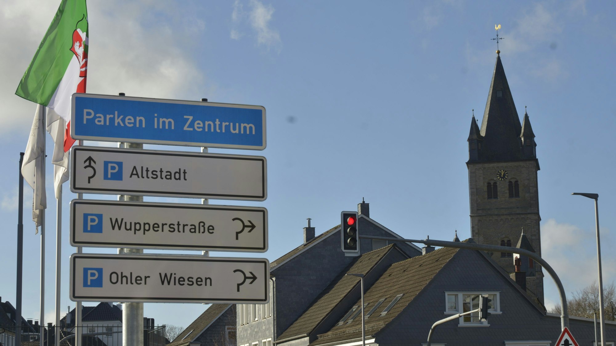 Das Parkleitsystem zeigt auf verschiedenen Schildern die Richtungen der Parkplätze in der Altstadt, der Wupperstraße und an den Ohler Wisen an. Im Hintergrund ist eine Kirche zu sehen.