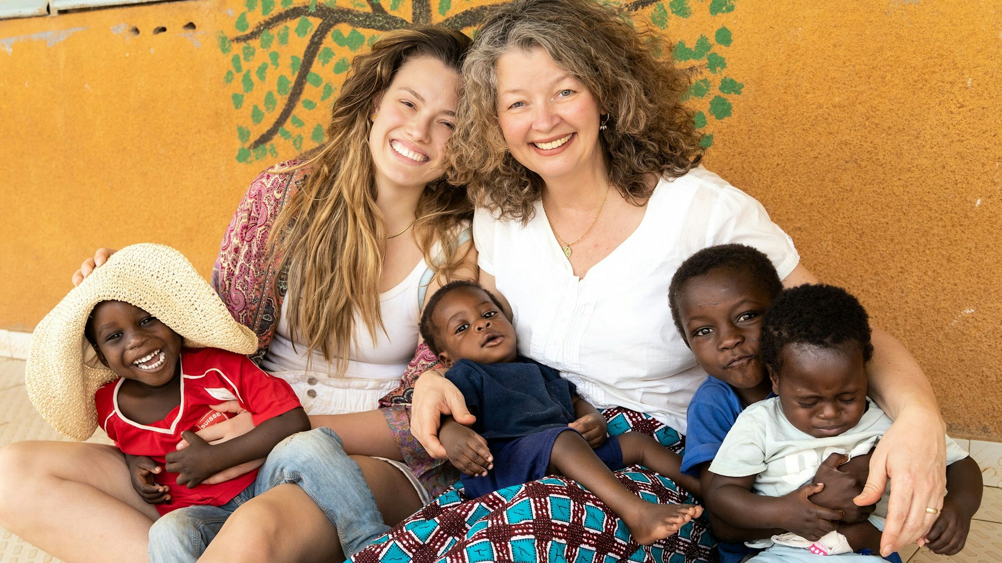 Sarah Prothmann und ihre Mutter Susanne haben kleine Kinder aus dem Waisenheim auf dem Schoß.