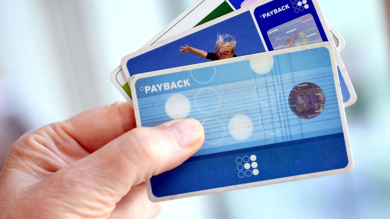 Eine Hand hält drei Payback-Karten wie einen Fächer.