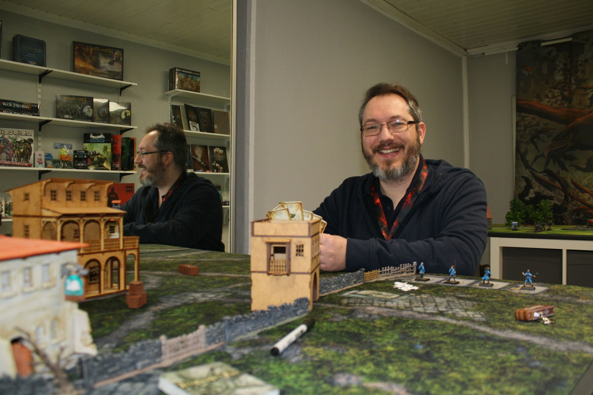 Dennis Graeper sitzt in seinem Laden vor einem Spielfeld.