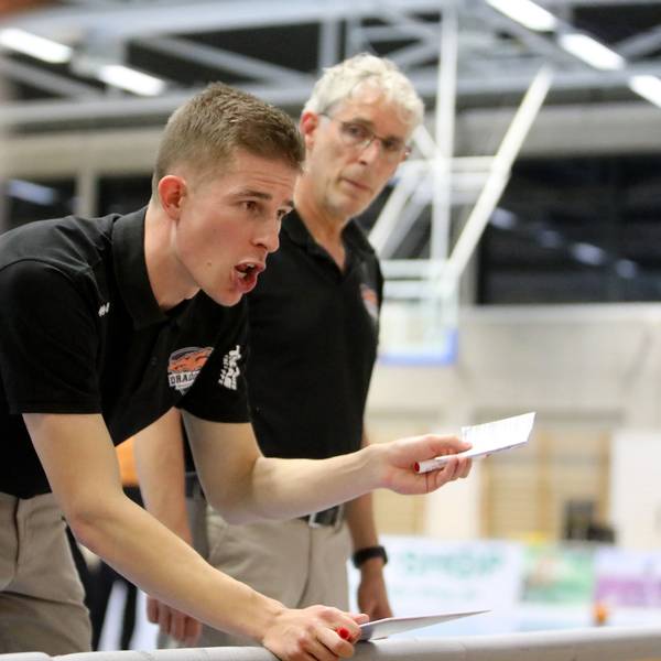 Der Rhöndorfer Cheftrainer Julius Thomas (vorne) hält einen Zettel in der Hand und instruiert seine Spieler. Co-Trainer Martin Otto hört aufmerksam zu.