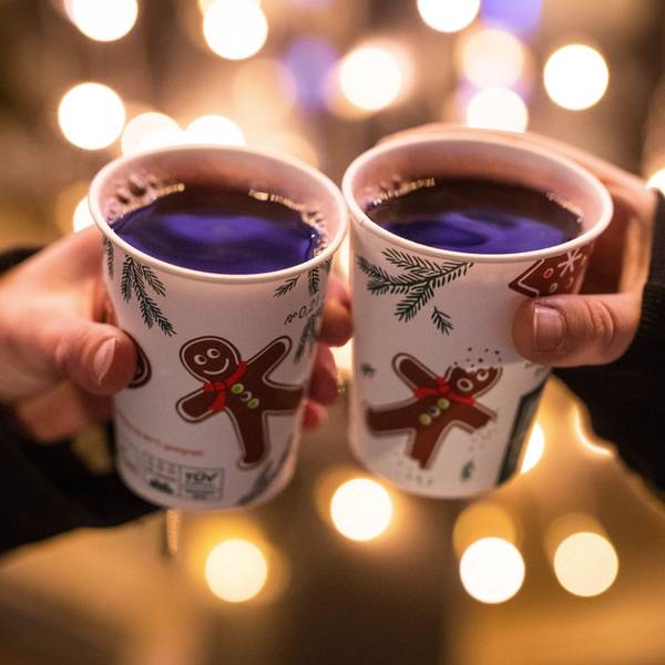 Zwei Frauen stoßen mit Glühwein gefüllten Bechern an.