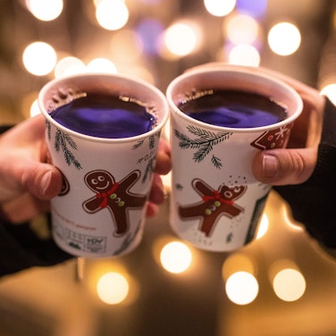 Zwei Frauen stoßen mit Glühwein gefüllten Bechern an.