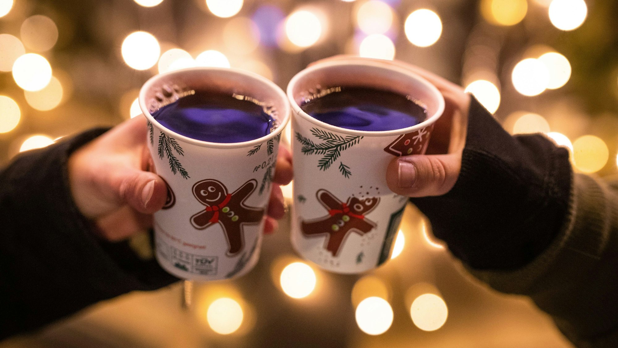 Zwei Frauen stoßen am Schlossplatz mit Glühwein gefüllten Bechern an. Symbolbild