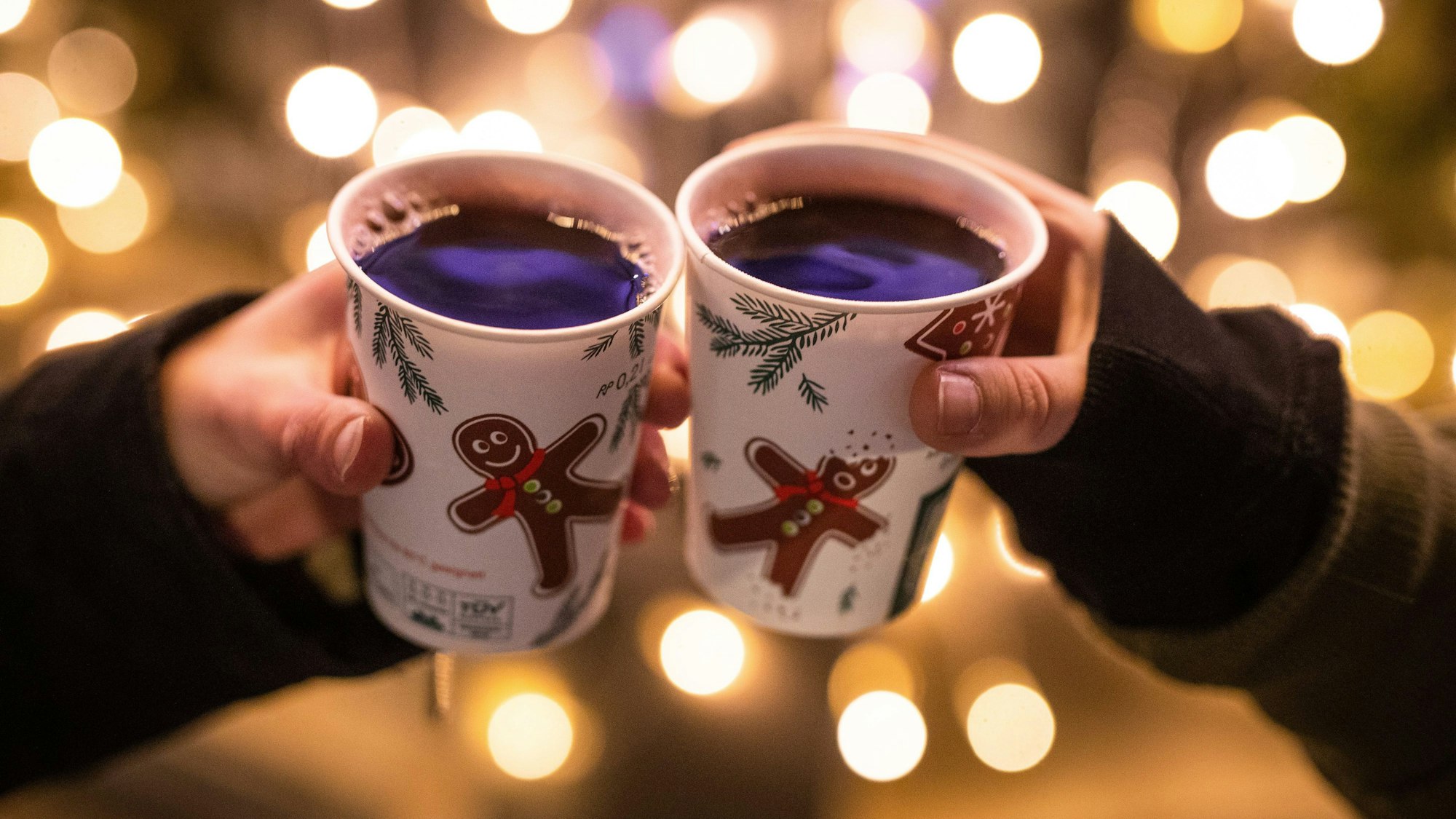 zwei Frauen stoßen mit Glühwein gefüllten Bechern an