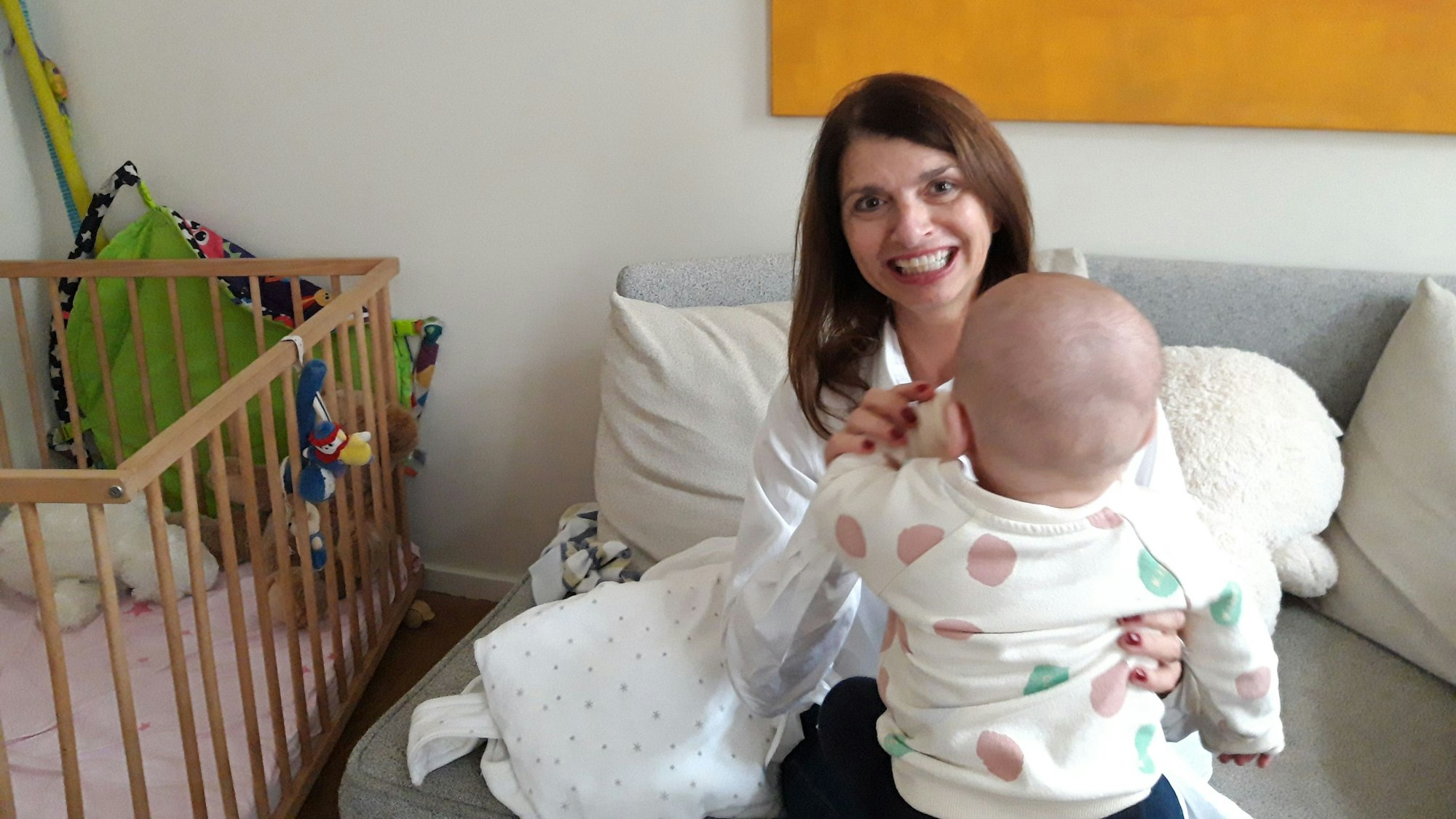 Andrea Kaletha hat ein kleines Kind auf dem Schoß und lächelt breit in die Kamera. Sie hat das Haus Andreka gegründet. Mit ihrem Team kümmert sie sich dort um sehr junge Mütter mit psychischen Schwierigkeiten.