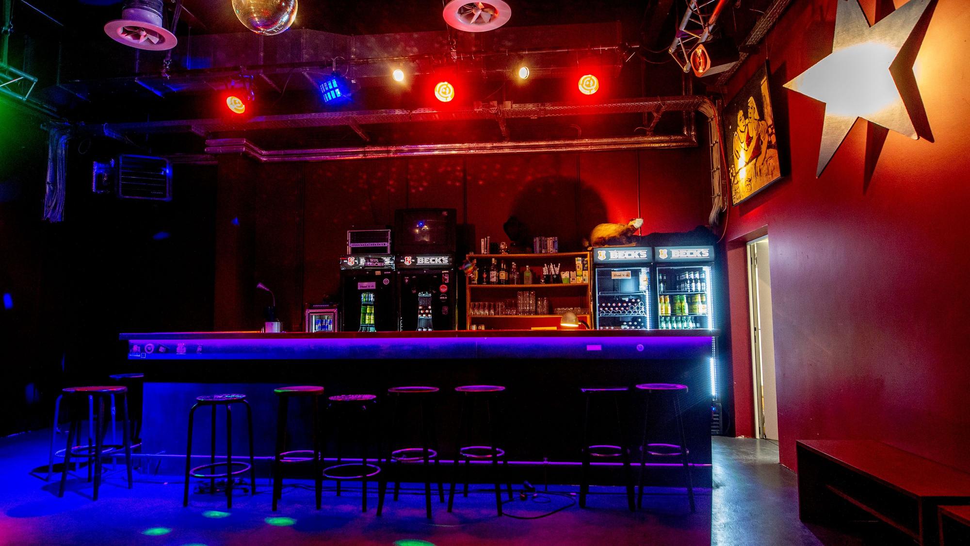 Die Bar des Gebäude 9, im schummrigen Licht aufgenommen. Recht wird ein Stern an der Wand angestrahlt.
