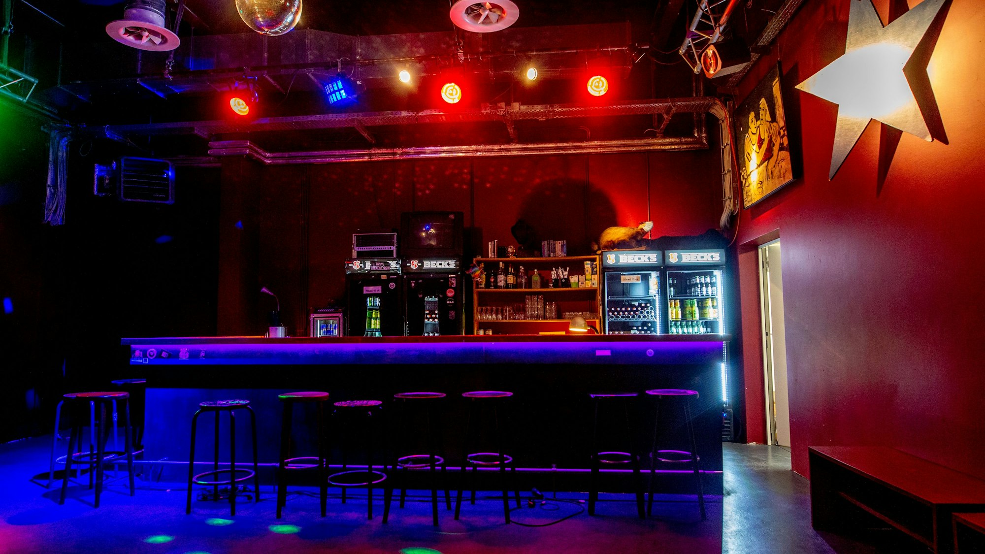 Die Bar des Gebäude 9, im schummrigen Licht aufgenommen. Recht wird ein Stern an der Wand angestrahlt.