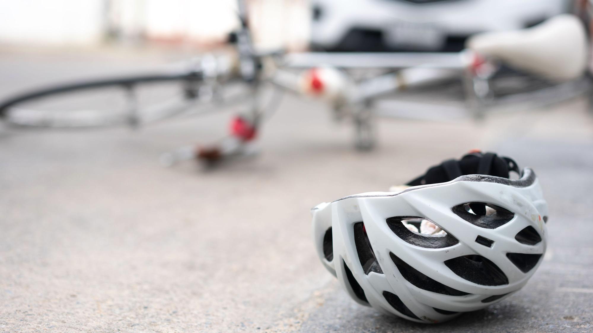 Ein Fahrradhelm liegt auf dem Asphalt, dahinter ein umgekipptes Fahrrad