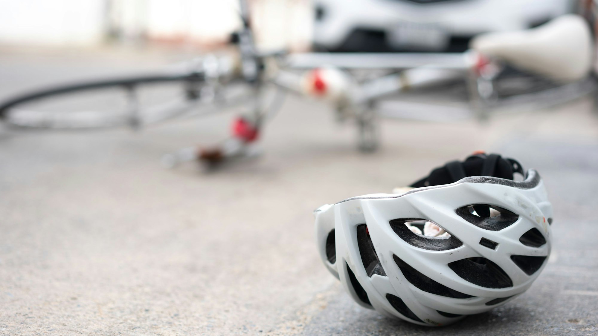 Ein Fahrradhelm liegt auf dem Asphalt, dahinter ein umgekipptes Fahrrad