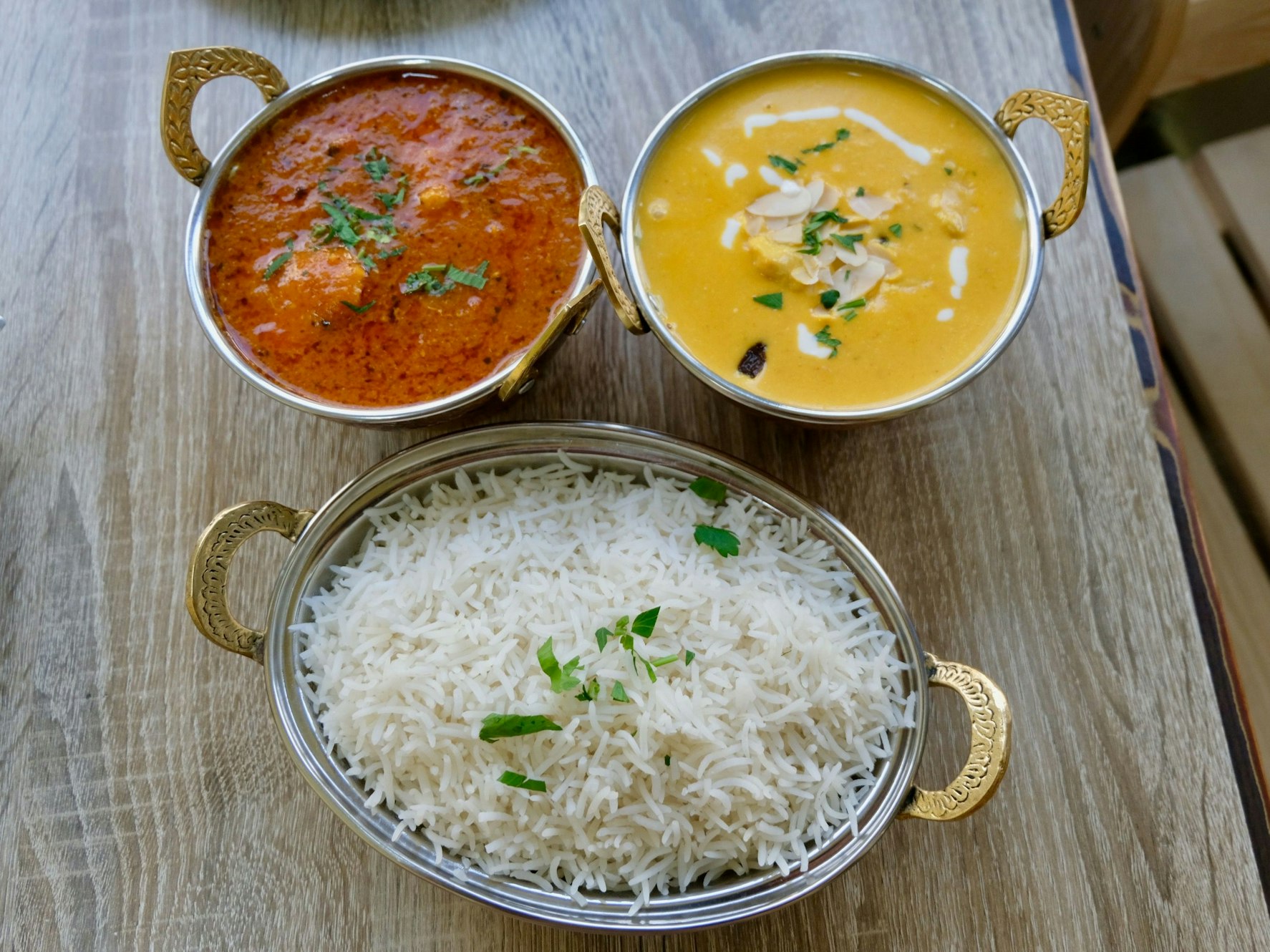 Rotes und gelbes indische Curry in goldenen Schalen wird im Curry Up mit Reis serviert.