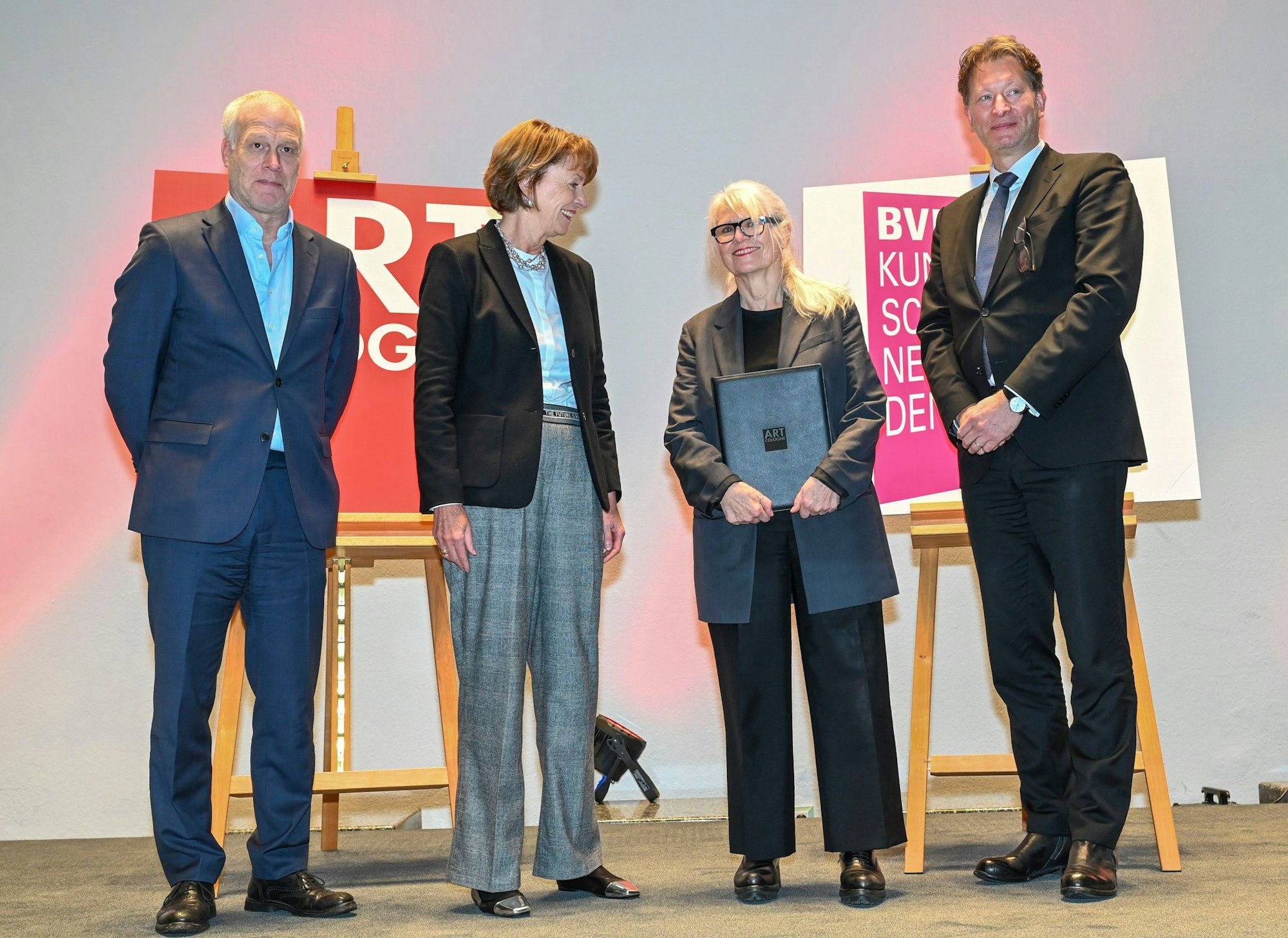Monika Sprüth steht bei der Preisverleihung auf der Bühne des Historischen Rathauses in Köln. Sie wird eingerahmt von Art-Cologne-Chef Daniel Hug,  Henriette Reker, Oberbürgermeisterin der Stadt Köln, und Kristian Jarmuschek, Vorsitzender des Bundesverbands Deutscher Galeristen