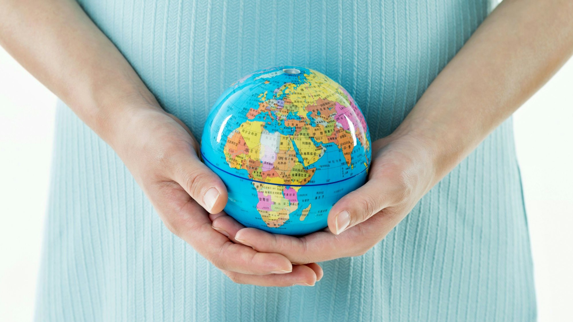 Schwangere Frau mit Globus vor dem Bauch