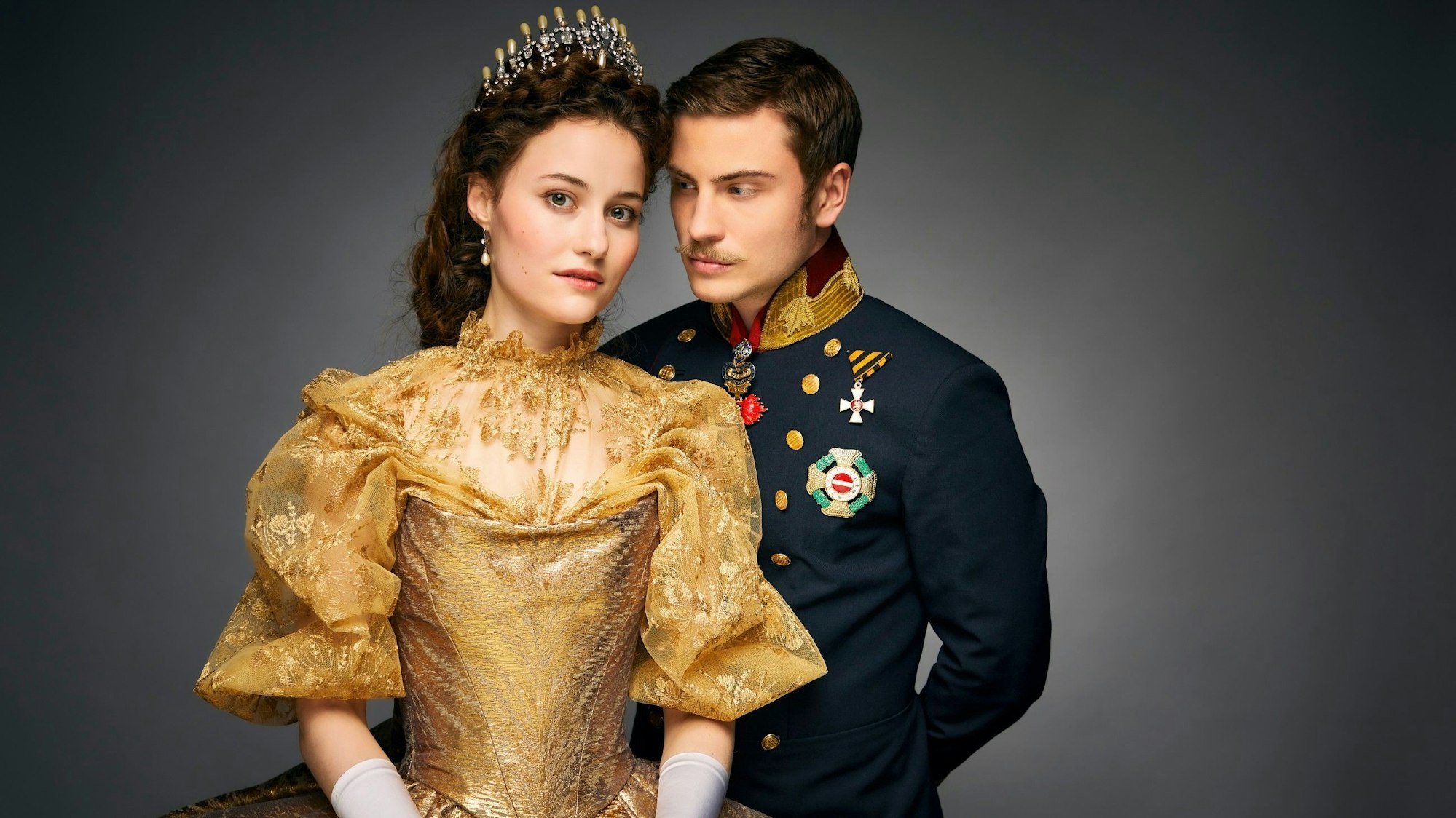 Dominique Devenport als Sisi und Jannik Schümann als Franz. Sie trägt ein goldenes Kleid, er eine dunkelblaue Uniform.