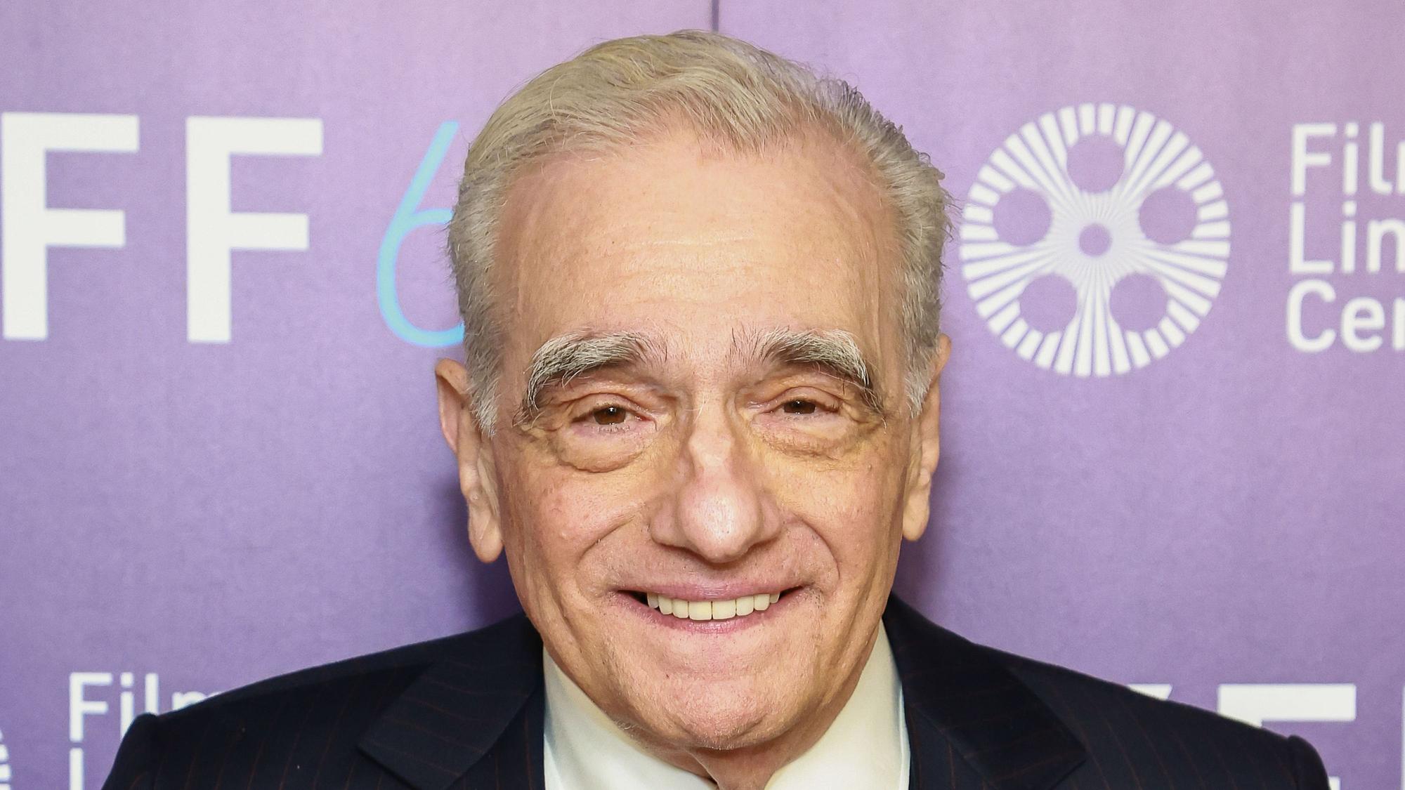 Regisseur Martin Scorsese lächelnd vor einer lila Filmwand.