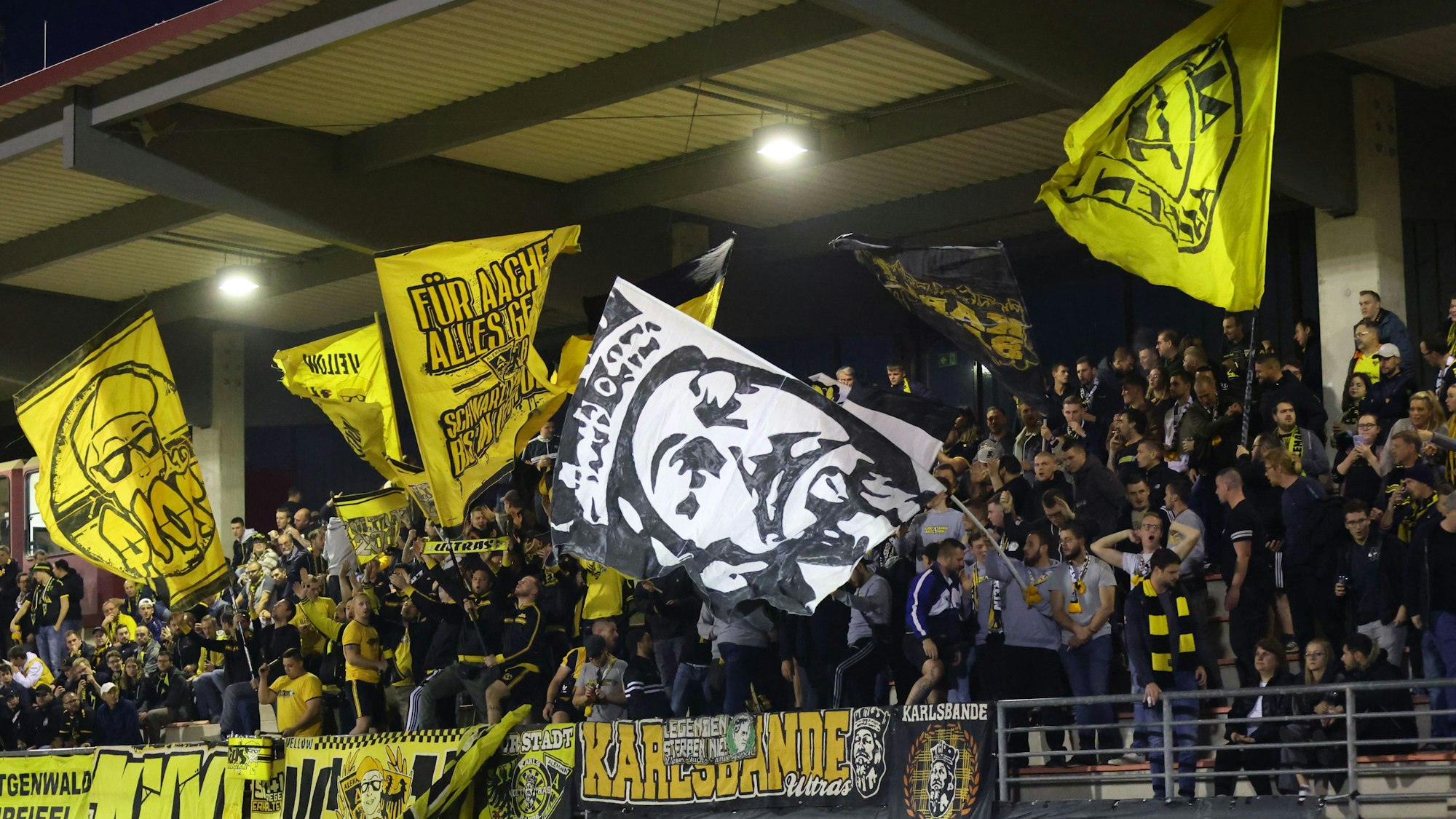 Menschenmenge im Stadion schwingt gelbe Fahnen.