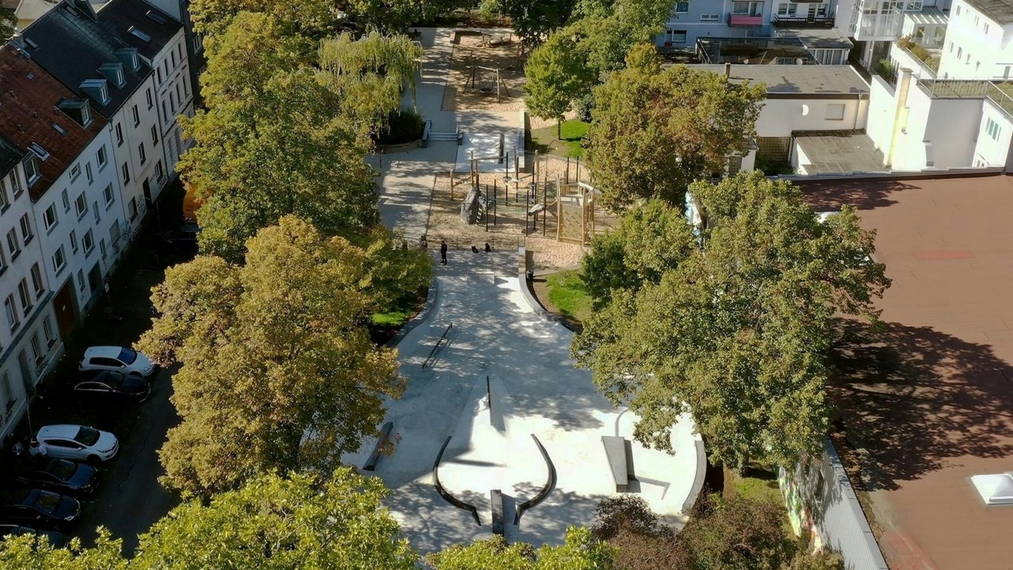 Der Spielplatz an der Keupstraße wurde vollkommen neu gestaltet. Auf dem Bild, das in der Vogelperspektive aufgenommen wurde, sieht man den neuen Skatepark sowie den Spielplatz umgeben von grünen Bäumen.