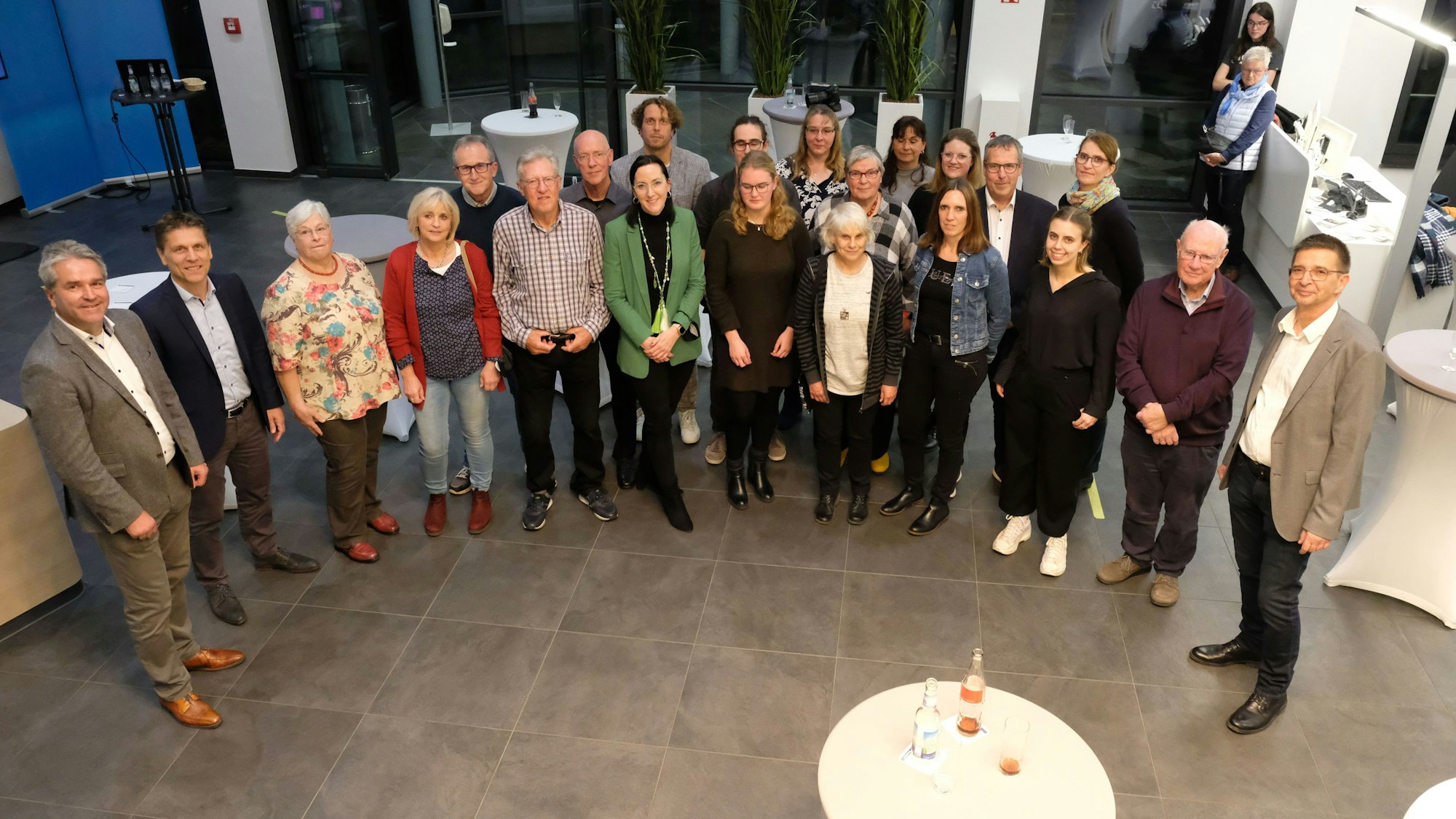 Über 20 Menschen stehen beisammen und lächeln in die Kamera.