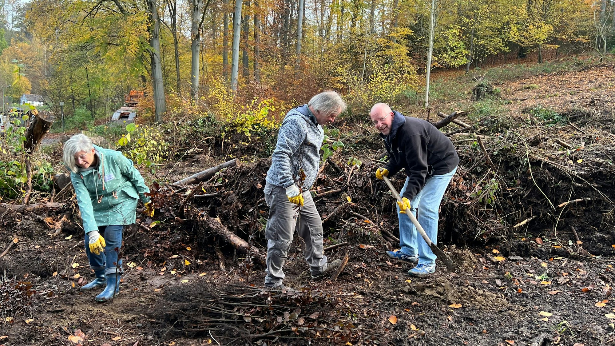 Anwohner graben Löcher in den matschigen Boden, um junge Bäume einzusetzen.