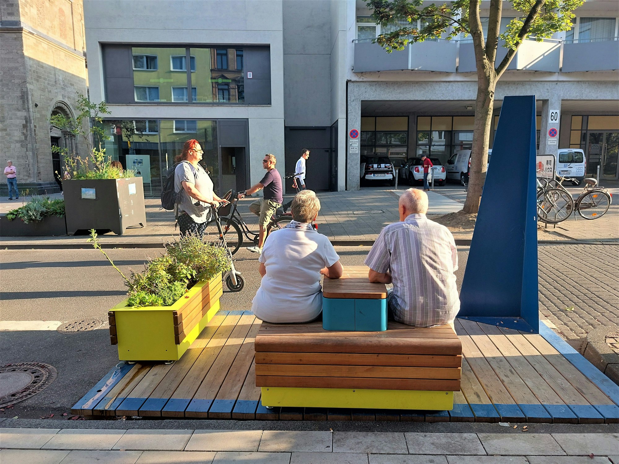 Zwei Menschen sitzen auf der Deutzer Freiheit auf einem Sitzmöbel.