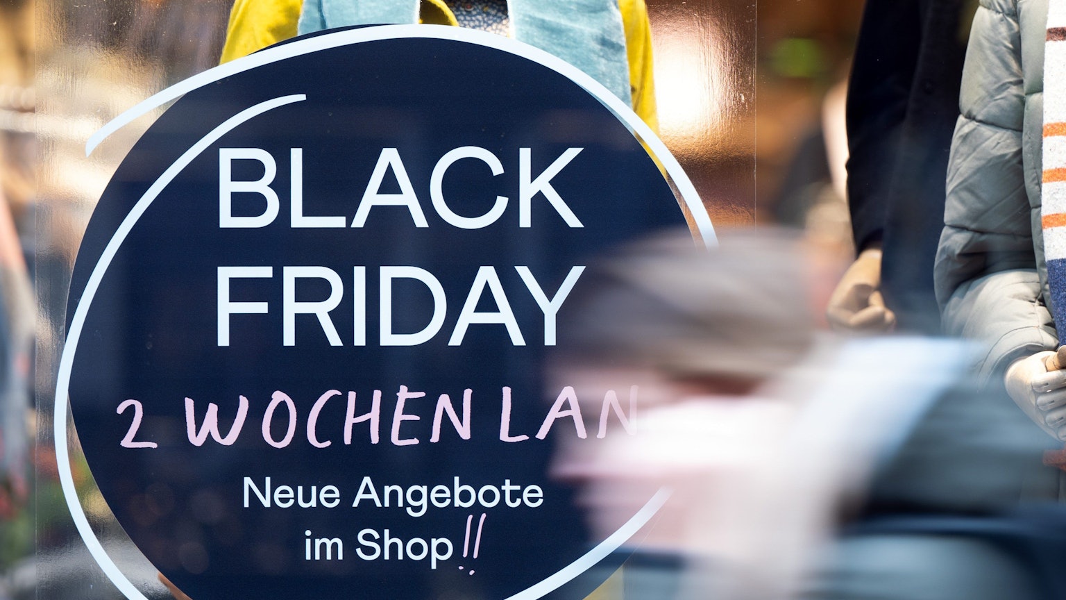 Eine Frau geht in Köln an einem Geschäft vorbei, das mit Black-Friday-Angeboten wirbt.