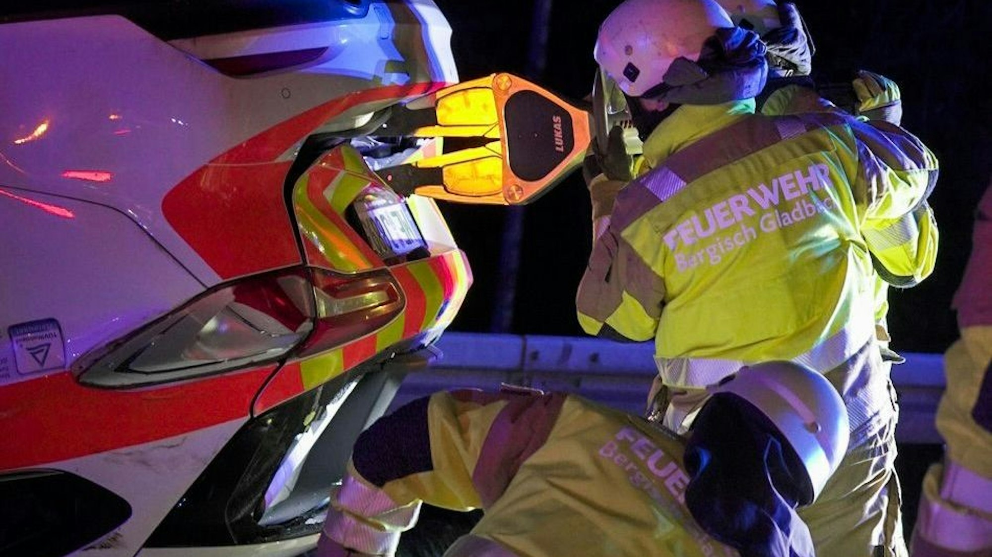 Feuerwehrleute öffnen den Kofferraum eines auf dem Dach liegenden Fahrzeugs mit hydraulischem Werkzeug.