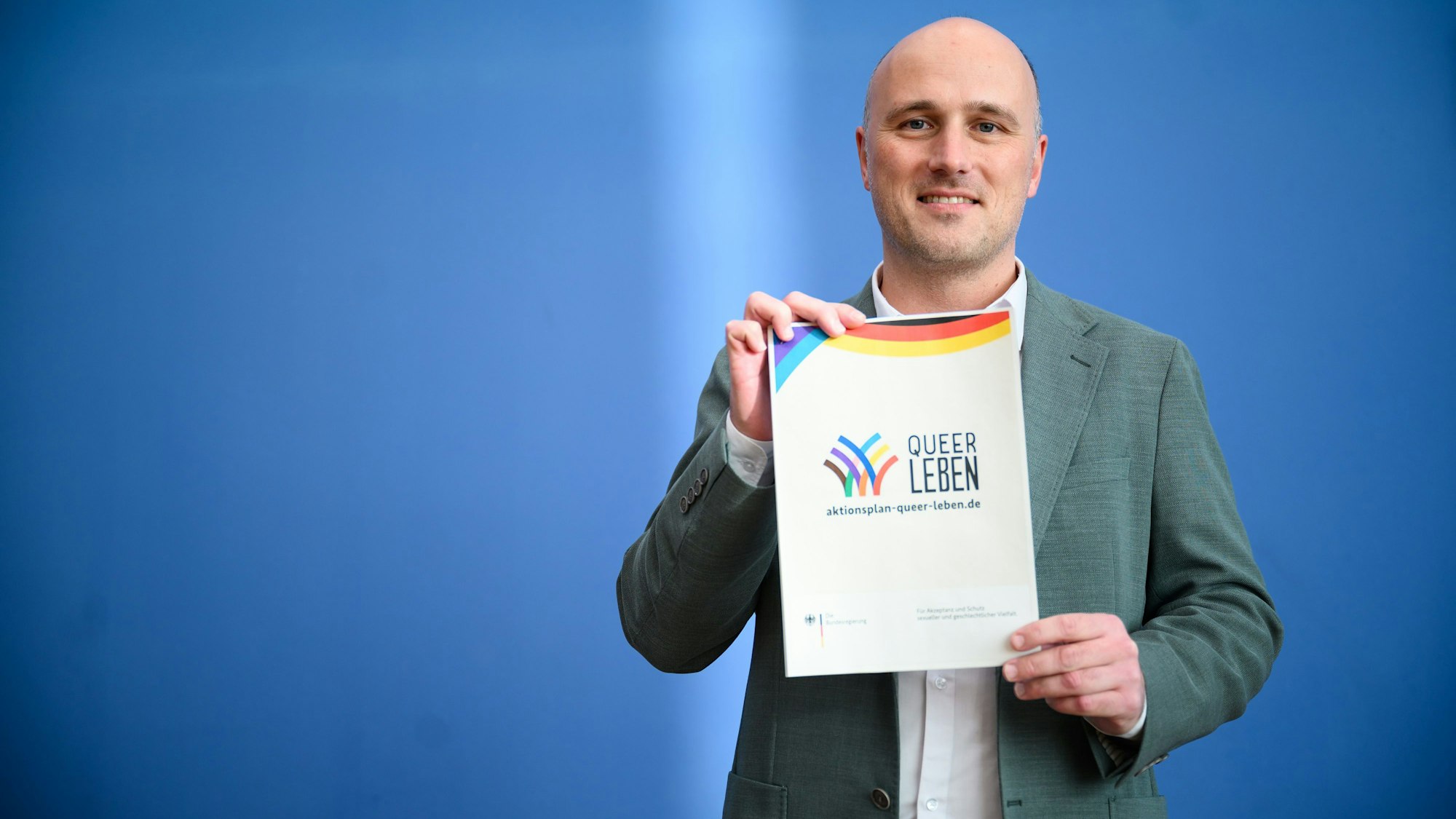 Sven Lehmann (Bündnis 90/Die Grünen), Parlamentarischer Staatssekretär im Bundesministerium für Familie, Senioren, Frauen und Jugend und Queer-Beauftragter der Bundesregierung, hält den ersten Aktionsplan der Bundesregierung «Queer leben» für Akzeptanz und Schutz sexueller und geschlechtlicher Vielfalt hoch