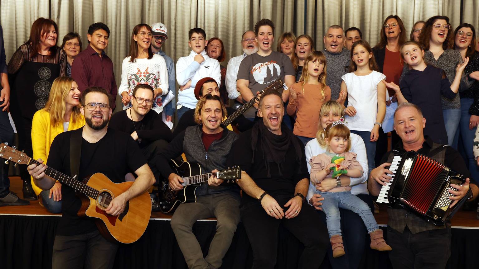 Der Familien-Workshop im Kölner Maritim-Hotel gehört zu den Höhepunkten der Jubiläumsausstellung „50 Jahre Höhner“ des Kölnischen Stadtmuseums. Menschen singen in drei Reihen sitzend und stehend auf einer Bühne.