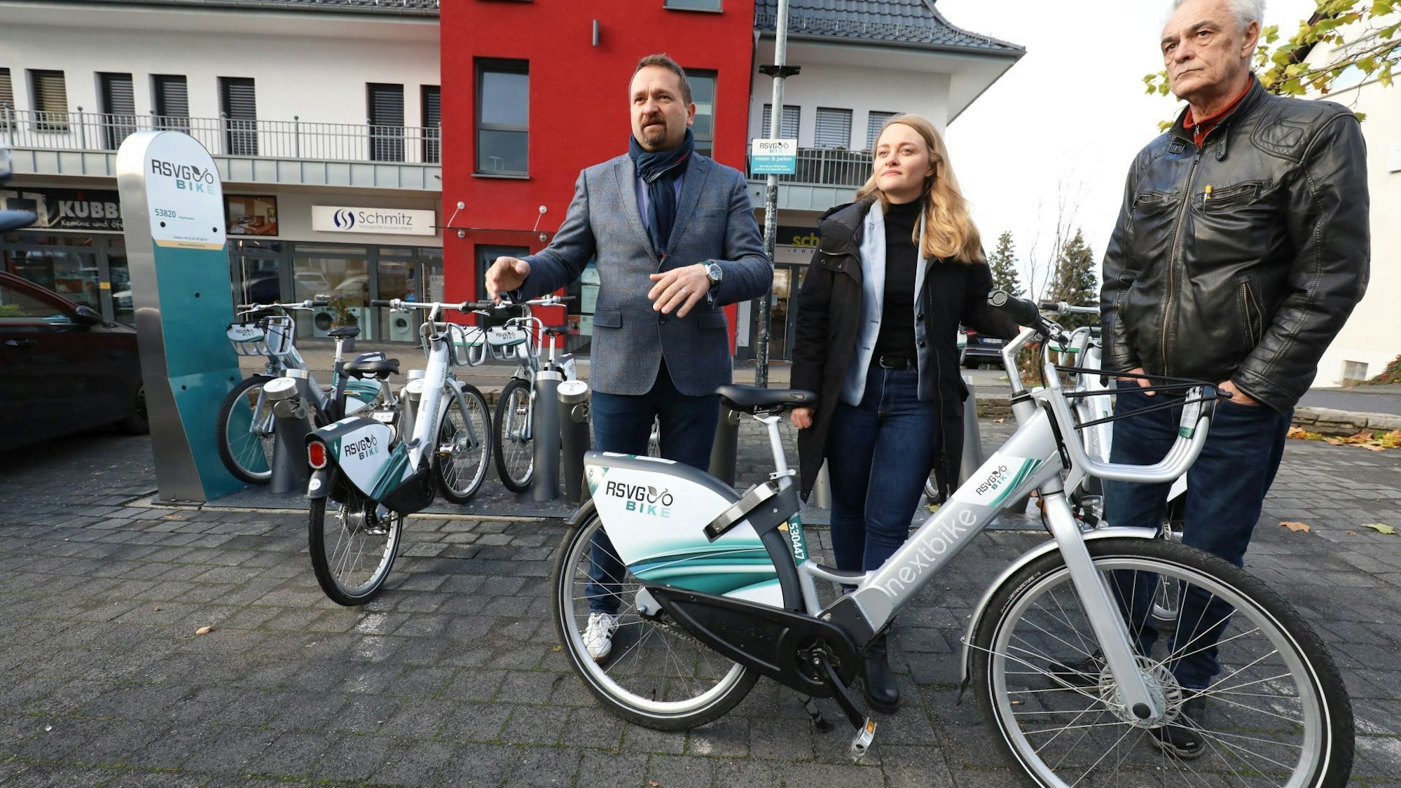 Eine Frau und zwei Männer – Holger Heuser, Kathrin Schmidt und Uwe Weingarten – stehen vor einer Ladestation für E-Bikes und zeigen eines der Fahrräder.